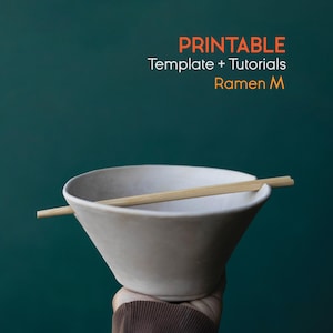 Op de afbeelding: Een witte keramische ramenkom met een paar houten eetstokjes, tegen een teal achtergrond. De tekst in oranje en wit luidt "PRINTABLE Template + Tutorials Ramen M".