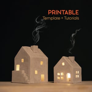 May include: Two small, beige ceramic house-shaped candle holders with lit candles inside, emitting a warm glow. Smoke rises from the chimneys. The image includes the text "PRINTABLE Template + Tutorials" in orange.
