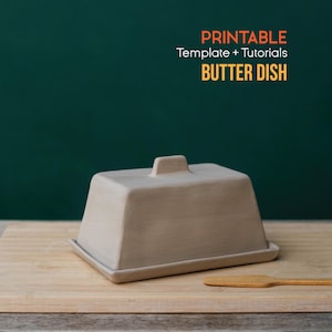 May include: A beige butter dish with a rectangular lid and a small handle, resting on a wooden cutting board. A small wooden butter knife is next to the dish. The text "PRINTABLE Template + Tutorials BUTTER DISH" is in the background.