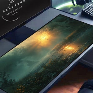 May include: A large, rectangular, black gaming mouse pad with a scenic image of a forest with a sunset in the background. The mouse pad is on a desk with a computer monitor, keyboard, and headphones.