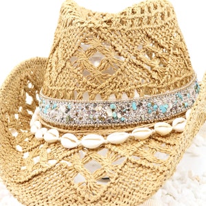 May include: A straw cowboy hat with a beaded trim and white seashells around the crown.