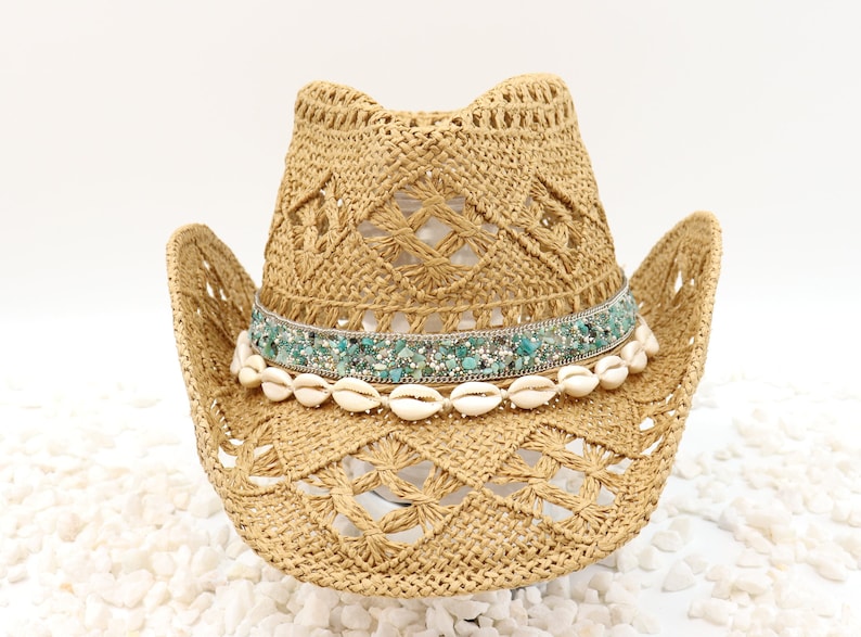 May include: A straw cowboy hat with a turquoise and silver beaded band and white shell accents.