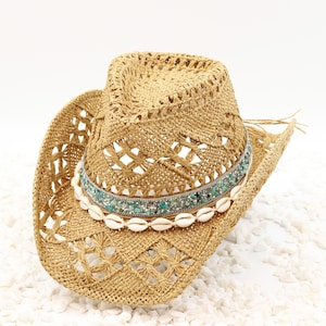 May include: A straw cowboy hat with a turquoise and white beaded band and a row of white seashells.
