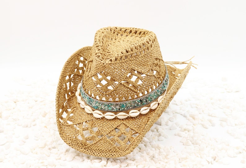 May include: A straw cowboy hat with a turquoise and white beaded band and a row of white seashells.