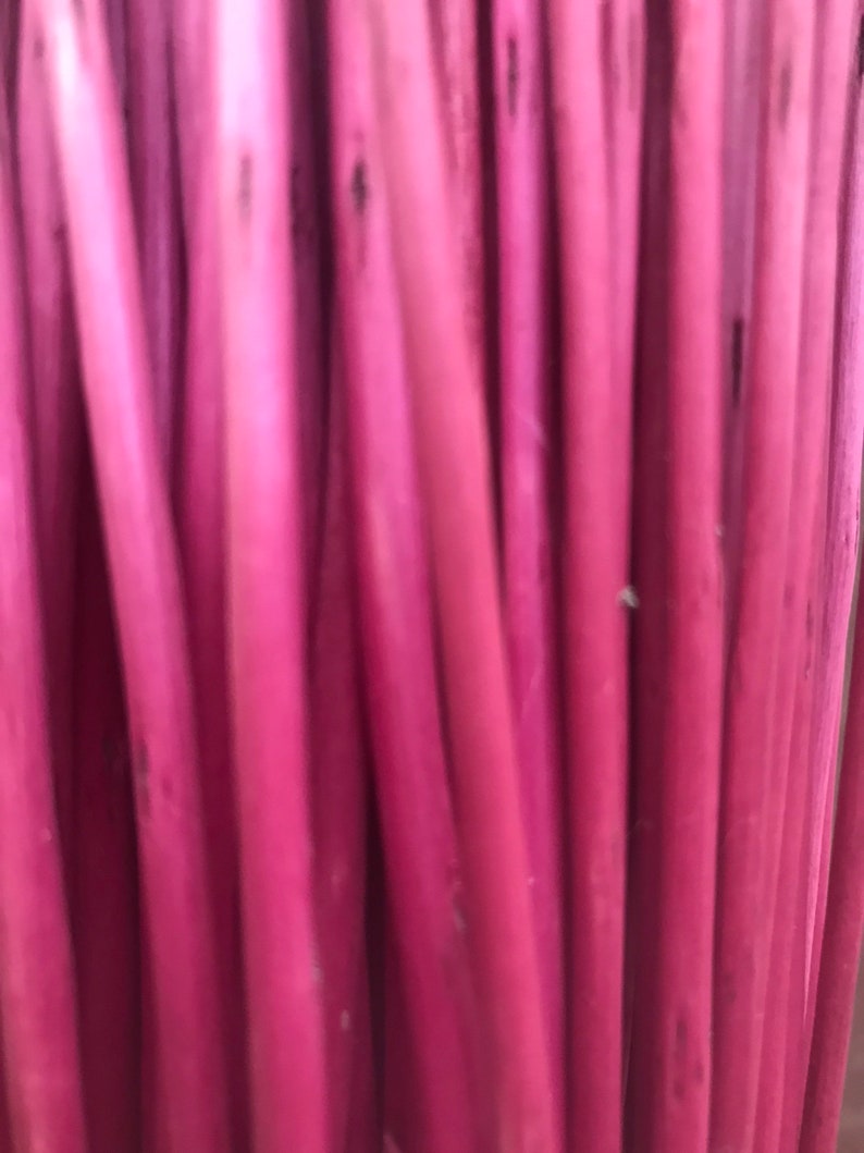 May include: A close-up of a bundle of thin, pink, wooden sticks.