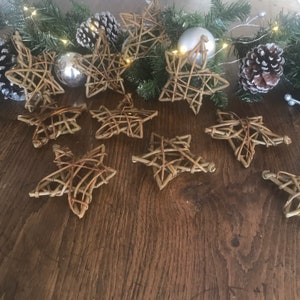 May include: A collection of ten brown twig star decorations. The stars are arranged on a wooden surface.