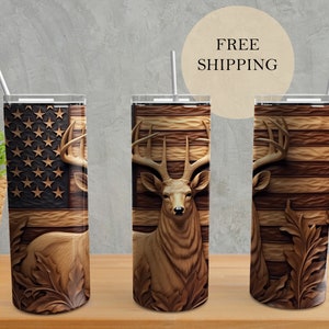May include: Three stainless steel tumblers with a wood-grain design featuring a carved deer head and an American flag. The tumblers are on a wooden surface.