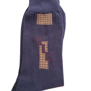 May include: A pair of dark blue socks with a brown patterned design. The pattern features a grid of small squares.