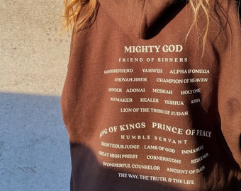 May include: Brown hoodie with a white print that reads "Mighty God, Friend of Sinners" and lists many of God's titles and attributes.