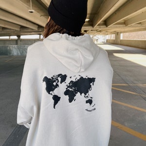 May include: White hoodie with a black world map print on the back. The text "daniel 7:14" is printed below the map.