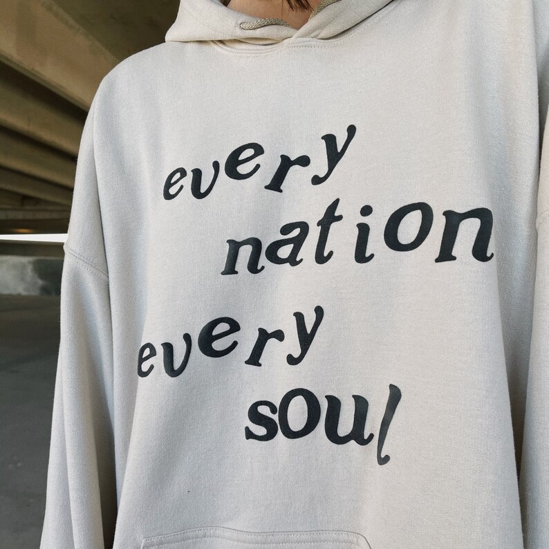 May include: A beige hoodie with the text "every nation every soul" printed in black.