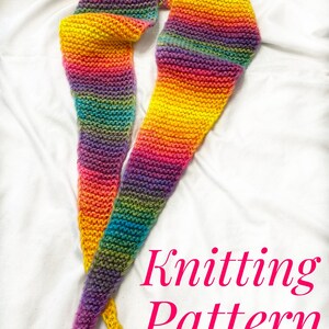 Könnte beinhalten: Ein bunter Regenbogen-gestreifter Strickschal mit Quasten. Der Schal liegt auf einer weißen Oberfläche mit dem Text "Knitting Pattern" in Pink.