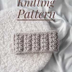Può includere: Primo piano di una fascia per capelli a maglia di colore grigio chiaro. La fascia ha un motivo testurizzato ed è appoggiata su una superficie bianca e soffice. Il testo "Knitting Pattern" è scritto in marrone sopra la fascia.