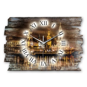 Könnte beinhalten: Eine Wanduhr aus Holz mit einem Stadtbild. Das Zifferblatt der Uhr zeigt römische Ziffern und einen silberfarbenen Stunden- und Minutenzeiger. Die Stadt ist eine Nachtszene mit einer Brücke und Gebäuden, die von Lichtern beleuchtet werden.