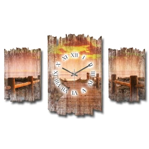 Könnte beinhalten: Ein dreiteiliges Wanduhr-Set mit einer Sonnenuntergangsszene mit einem Holzzaun. Die zentrale Uhr hat römische Ziffern und Zeiger. Das Kunstwerk ist auf Holz mit einem verwitterten, rustikalen Aussehen gedruckt.