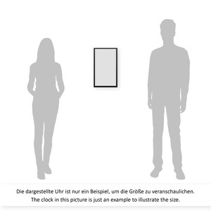 May include: A black framed rectangular clock with a white face. The clock is shown next to a silhouette of a person to illustrate the size.
