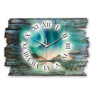 Könnte beinhalten: Eine rustikale Holzuhr mit römischen Ziffern und einem Hintergrundbild der Aurora Borealis über einem Gebirge und einem See. Das Zifferblatt der Uhr ist hellblau mit grün-violetten Nordlichtern.