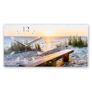 Könnte beinhalten: Eine Uhr mit einer Holzbank im Vordergrund und einer Strandszene mit Sonnenuntergang im Hintergrund. Das Zifferblatt der Uhr hat römische Ziffern und die Zeit ist auf 6:00 Uhr eingestellt.