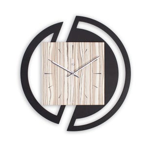 Könnte beinhalten: Eine moderne Wanduhr mit quadratischem Zifferblatt mit einem Holzmaserungsmuster in Beige- und Grautönen. Die Uhrzeiger sind silberfarben. Die Uhr ist in einem schwarzen, kreisförmigen Rahmen mit offenem Design angeordnet.