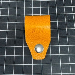 May include: A small, orange leather strap with a metal button and the word "FUN" embossed on the front.