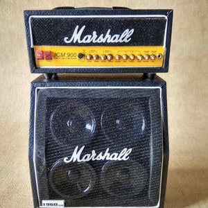 Puede incluir: Una cabeza de amplificador de guitarra Marshall JCM 900 negra con una placa frontal amarilla y un gabinete Marshall 1960 negro.