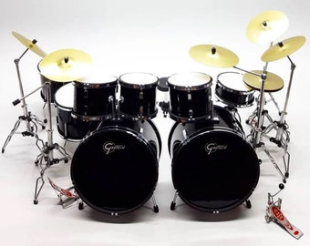 May include: A miniature black drum set with silver hardware and gold-colored cymbals. The drum set includes a bass drum, snare drums, tom-toms, and a hi-hat. The Gretsch logo is visible on the bass drum.