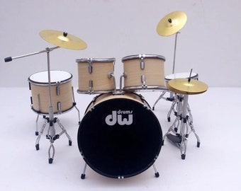 May include: A miniature drum set with a black bass drum that says "drums/dw" in white. The set includes a snare drum, two toms, and two cymbals.