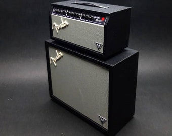 May include: A black and silver Fender guitar amplifier stack. The top amplifier has the text "Fender" and "Blackface" on the front. The bottom amplifier has the text "Fender" on the front.