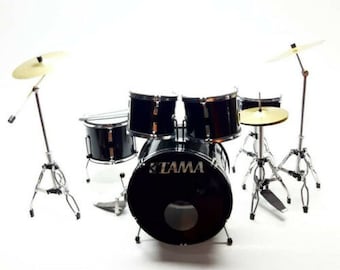 May include: A black Tama drum set with a bass drum, snare drum, two toms, and two cymbals. The drums are set up on stands with a hi-hat stand and a cymbal stand.