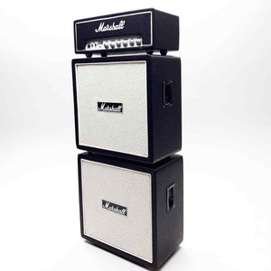 Könnte beinhalten: Ein Stapel aus drei schwarzen Marshall-Gitarrenverstärkern. Der obere Verstärker ist kleiner als die beiden darunter. Alle drei Verstärker haben einen weißen Lautsprechergrill und ein schwarzes Marshall-Logo.