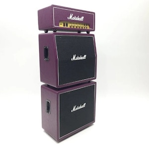 Könnte beinhalten: Ein Stapel aus drei violetten Marshall-Gitarrenverstärkern. Der oberste Verstärker hat das Wort "Marshall" auf der Vorderseite aufgedruckt. Der mittlere Verstärker hat das Wort "Marshall" auf der Vorderseite aufgedruckt. Der unterste Verstärker hat das Wort "Marshall" auf der Vorderseite aufgedruckt.