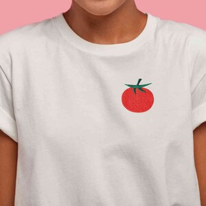 May include: White t-shirt with a red tomato embroidered on the front.