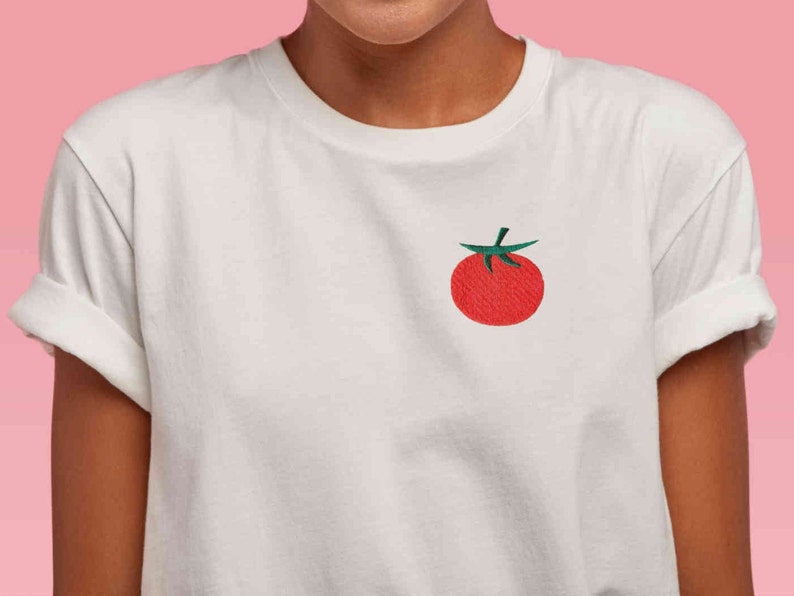 May include: White t-shirt with a red tomato embroidered on the front.