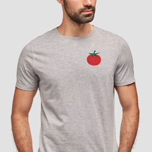 May include: A gray t-shirt with a red tomato graphic on the front.