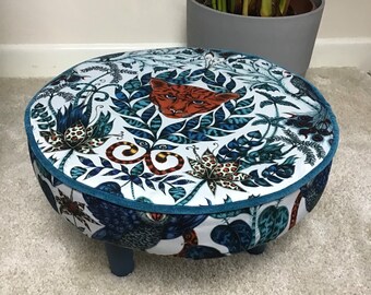 Round footstool featuring Emma Shipley Amazon print cotton in blue and white with contrasting teal colour piped edging and painted wood legs