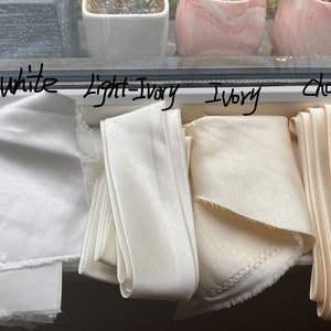 May include: Four fabric swatches in different shades of white, labeled "off-white", "light ivory", "ivory", and "champagne".