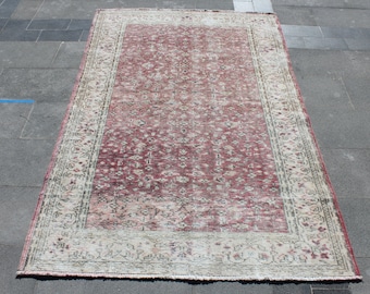 May include: A vintage rug with a pink and cream color scheme. The rug has a floral pattern and a border with a geometric design.