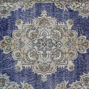 May include: A vintage rug with a blue background and a beige floral pattern. The rug has a worn and faded look, giving it a rustic and antique feel.