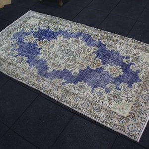 May include: A vintage rug with a blue background and a cream-colored floral pattern. The rug has a distressed look and is perfect for adding a touch of bohemian style to your home.