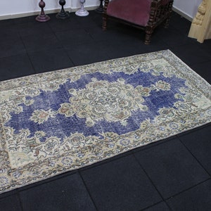 May include: A vintage rug with a blue background and a cream-colored floral pattern. The rug has a distressed look and is perfect for adding a touch of bohemian style to any room.