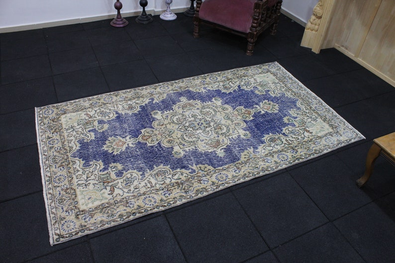 May include: A vintage rug with a blue background and a cream-colored floral pattern. The rug has a distressed look and is perfect for adding a touch of bohemian style to any room.