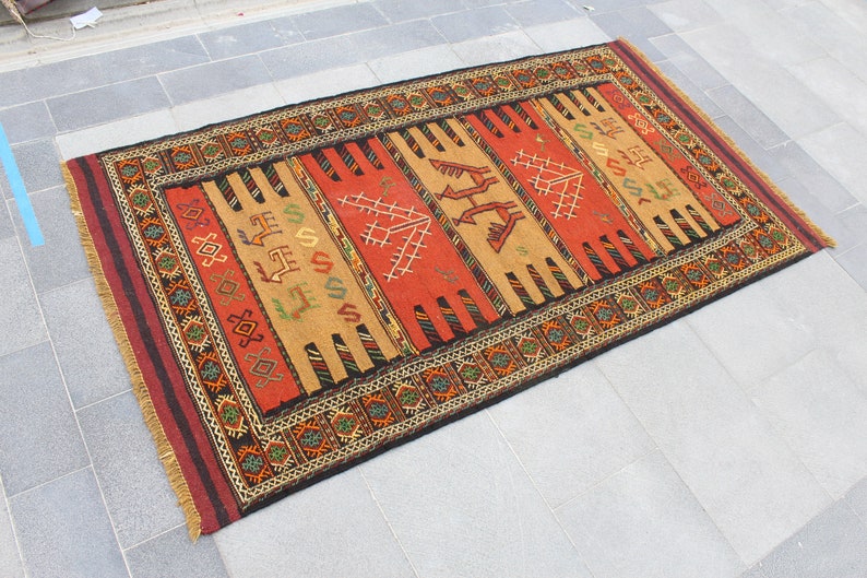 May include: A traditional Turkish rug with a red, orange, and brown color scheme. The rug features a geometric pattern with intricate details. The rug is made of wool and has a fringe border.