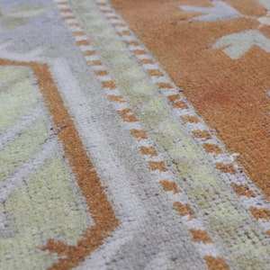 May include: Close-up of a woven rug with a geometric pattern in shades of brown, beige, and white.