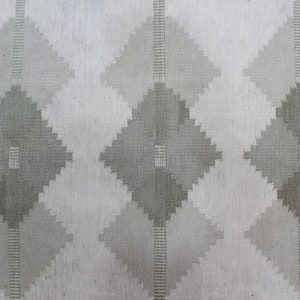 May include: A white fabric with a repeating pattern of gray diamond shapes. The diamonds are made up of smaller, overlapping squares.