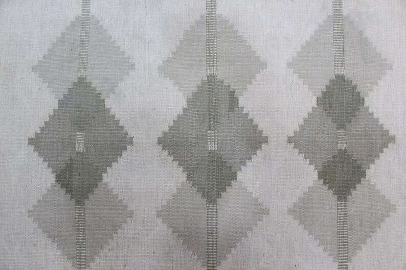 May include: A white fabric with a repeating pattern of gray diamond shapes. The diamonds are made up of smaller, overlapping squares.