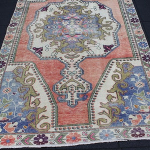 May include: A vintage rug with a floral pattern in shades of pink, blue, and green. The rug has a cream-colored background and a border with a repeating pattern.