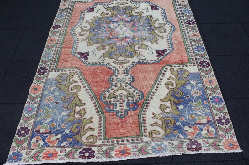 May include: A vintage rug with a floral pattern in shades of pink, blue, and green. The rug has a cream-colored background and a border with a repeating pattern.