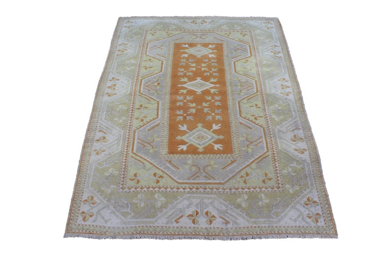 May include: A vintage rug with a geometric pattern in shades of orange, beige, and white. The rug has a central medallion with a diamond shape and a border with a repeating pattern.