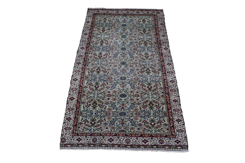 May include: A cream-colored rug with a floral pattern in shades of red, blue, and green. The rug has a border with a repeating pattern of flowers and leaves.