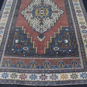 May include: A vintage rug with a red center and blue and white border. The rug has a traditional Persian design with intricate floral patterns.
